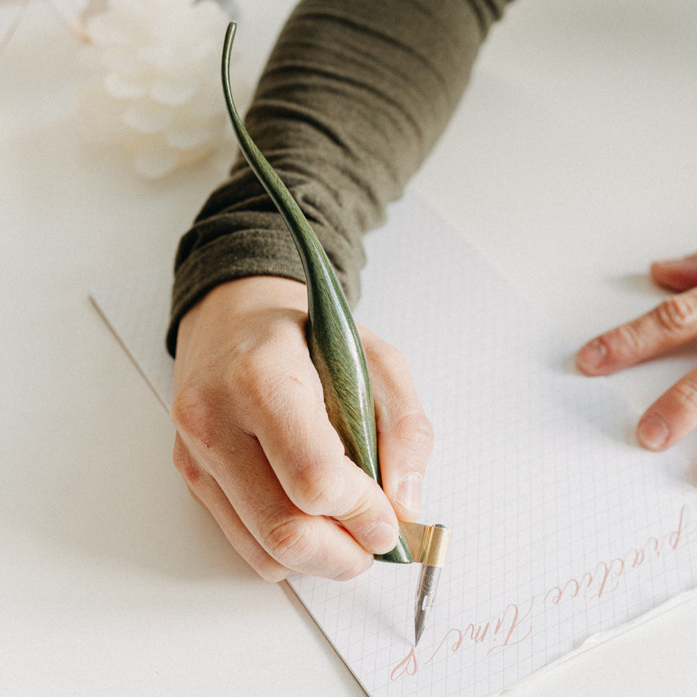 Person writing on a card with a pen, on a light surface.